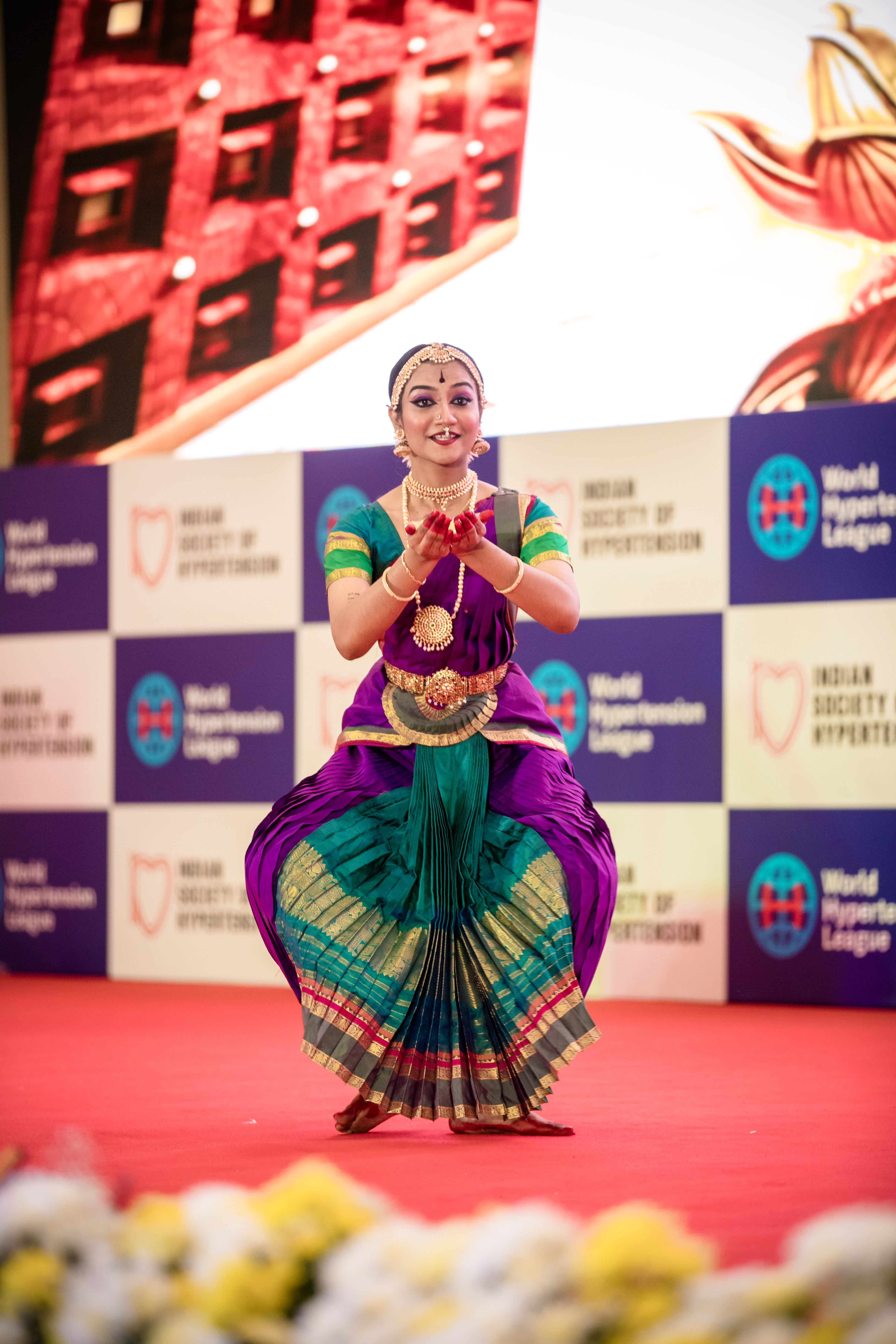 Dancers in vivid costumes performing in front of a colourful LED video wall